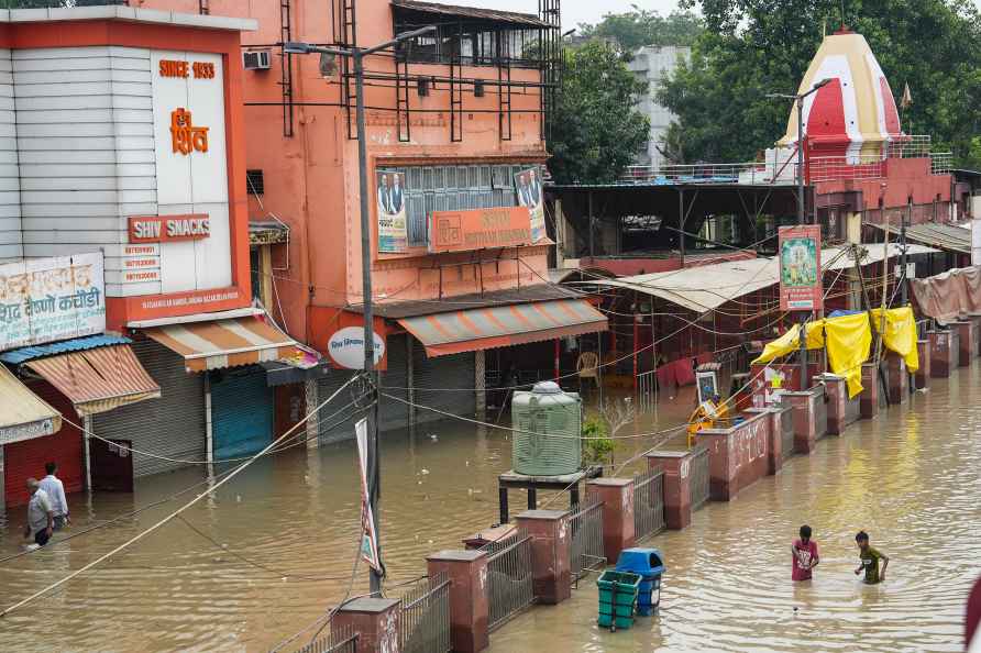 New Delhi: Locals wade through a flooded road near Marghat Wale ...