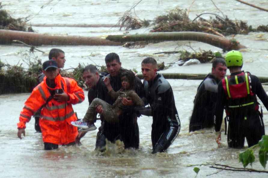 Emergency team members rescue a young girl during floods in a campsite...