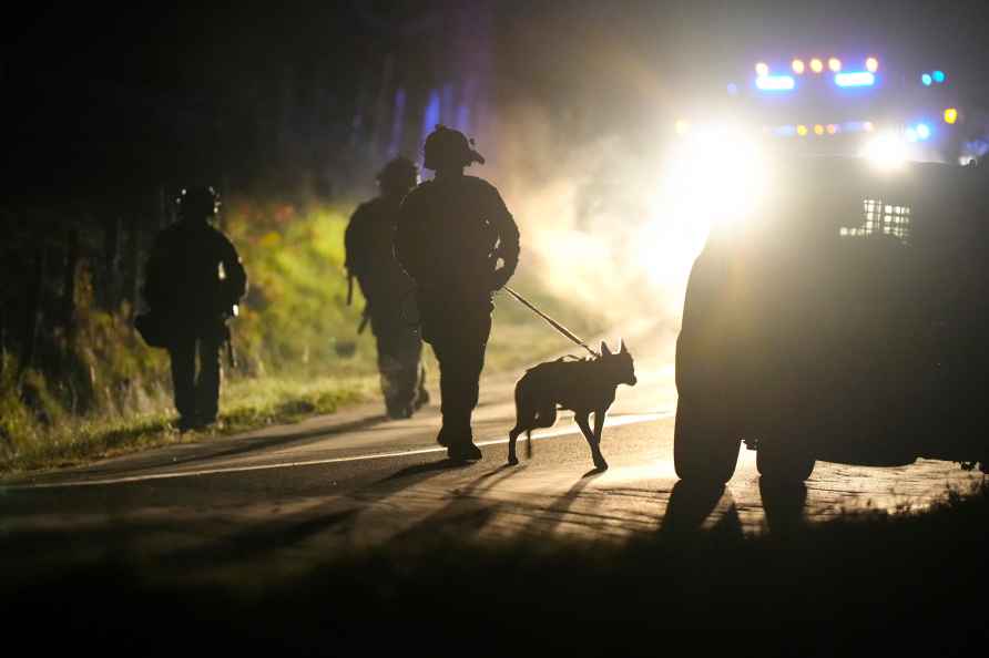 A member of law enforcement walks with a police dog outside a property...