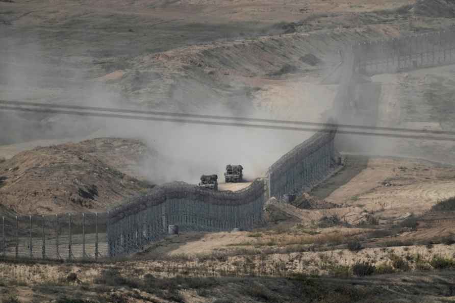 Israeli armoured vehicles drive along the fence around the Gaza Strip