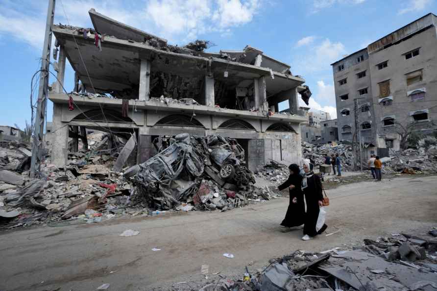 Palestinians walk past the buildings destroyed