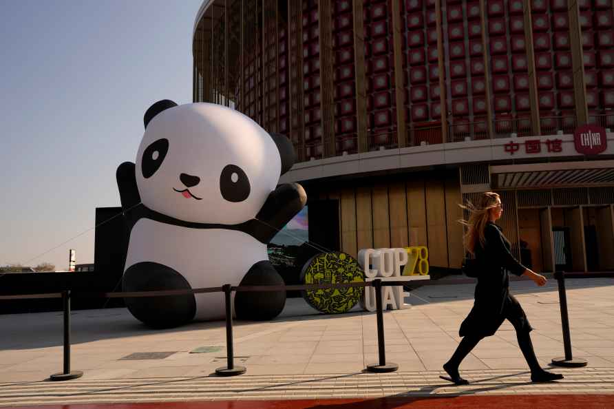 A woman walks outside of the China Pavilion near an inflatable panda...