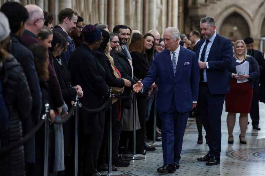 Britain's King Charles greets people as he visits the Royal Courts...