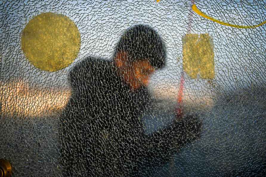 A man, seen through a broken glass, prepares his line as he fishes...