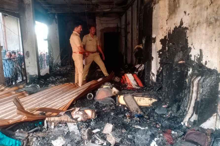 Police personnel examine a burnt shop