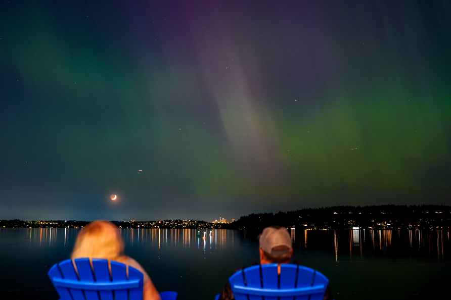 People view the northern lights, or aurora borealis, as they glow...