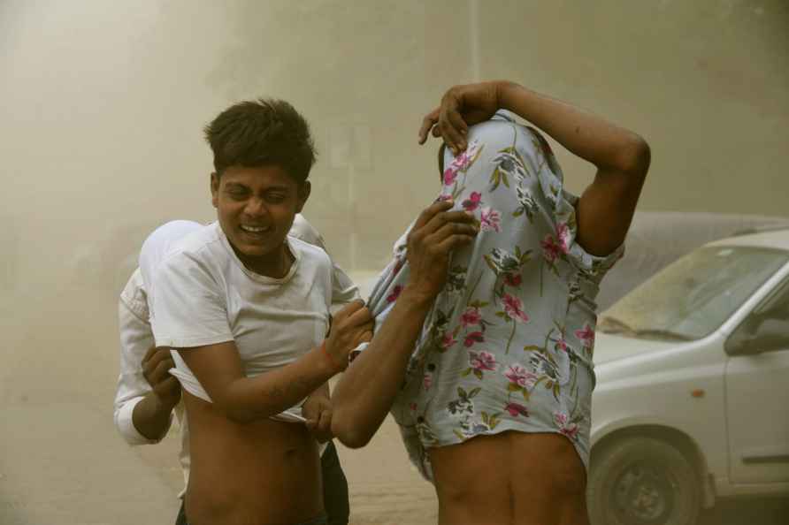 Patna: People cover themselves during a dust storm, in Patna, Thursday...