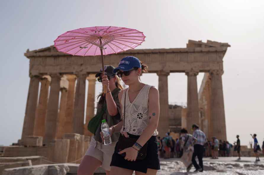 Tourists with an umbrella walk in front of the Parthenon