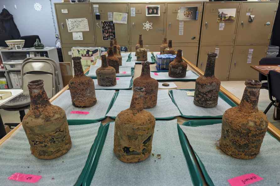 18th-century glass bottles that contained fruit sit inside an archaeology lab