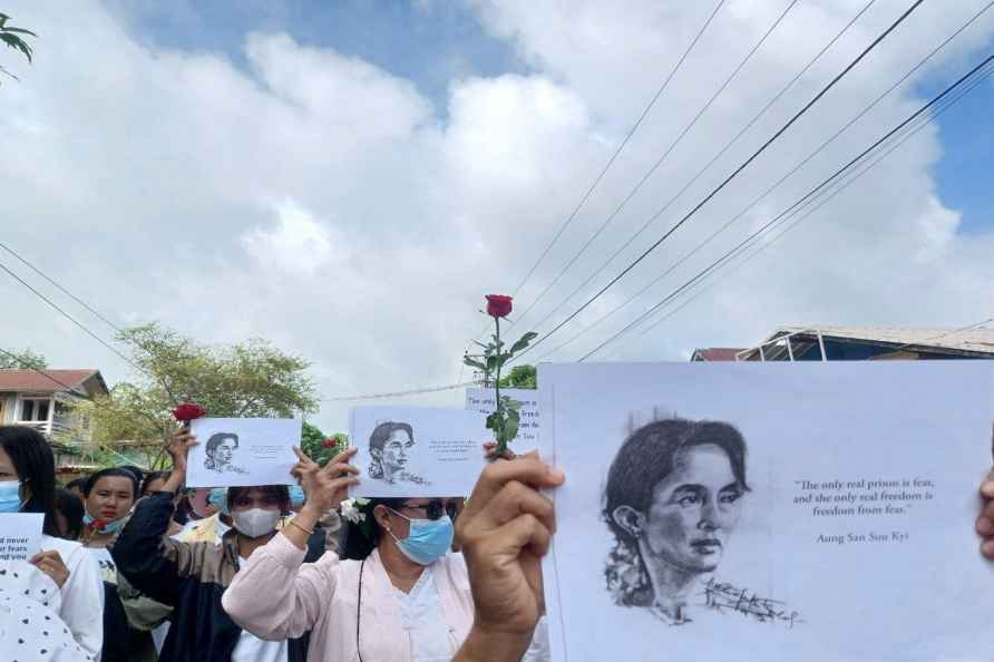 Demonstrators hold papers printed with Aung San Suu Kyi