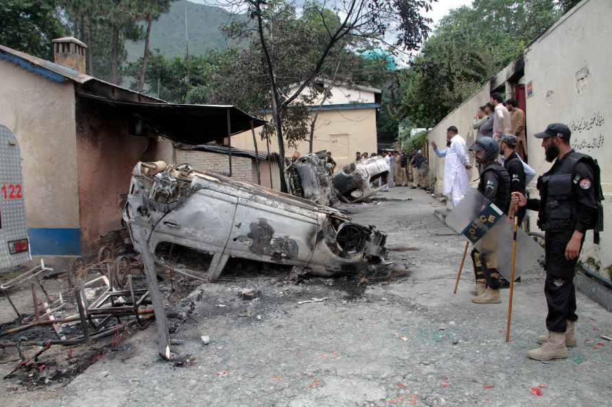 Police officers examine burnt vehicles which were torched by a Muslim mob in an attack