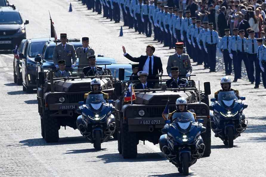 French President Emmanuel Macron waves from the command car as he...