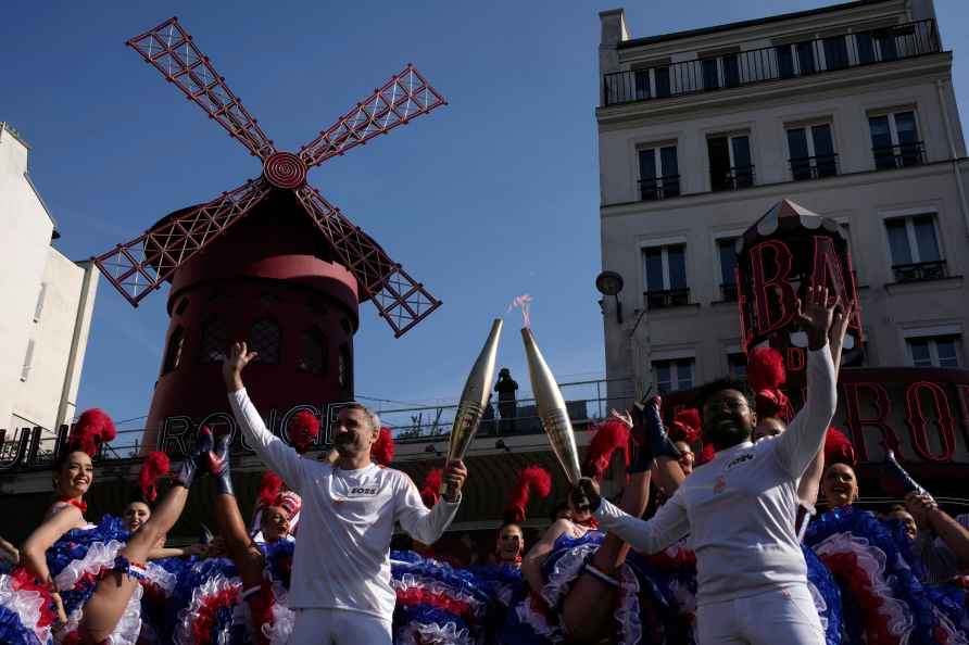 Torchbearers pose in front of the Moulin Rouge cabaret as dancers...