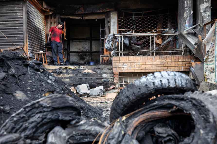 Nizam Uddin looks at the burnt tyres in front of his shop