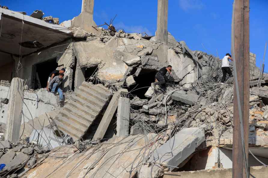 People search for victims at a destroyed building hit in an Israeli...