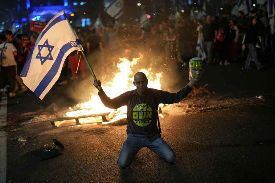 A protester holds an Israeli flag as Israelis light a bonfire during...