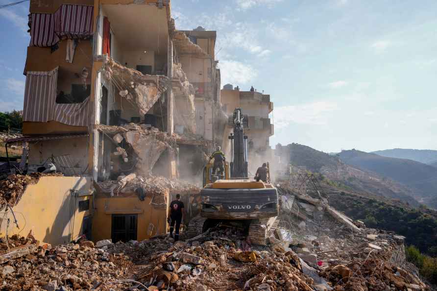 Rescue workers use excavators to remove the rubble of a destroyed...