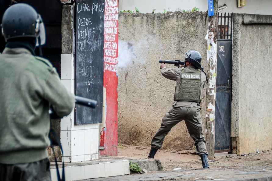 A police officer aims his weapon at protesters